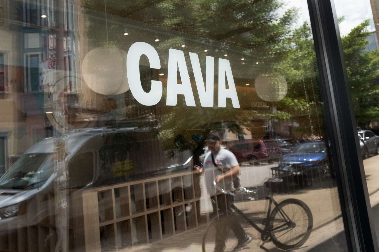The white Cava logo in the window of one of the company's restaurants
